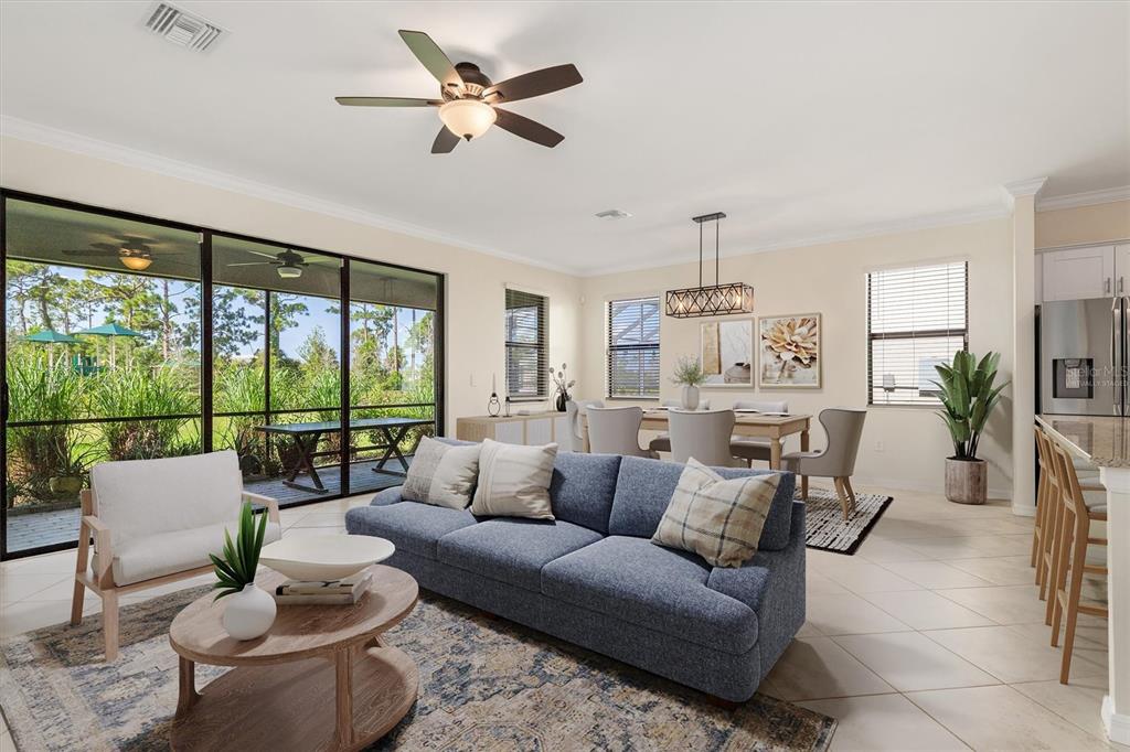 A living and dining area with a blue sofa, wood coffee table, and sliding glass doors — 11125 BALFOUR STREET, VENICE, FL