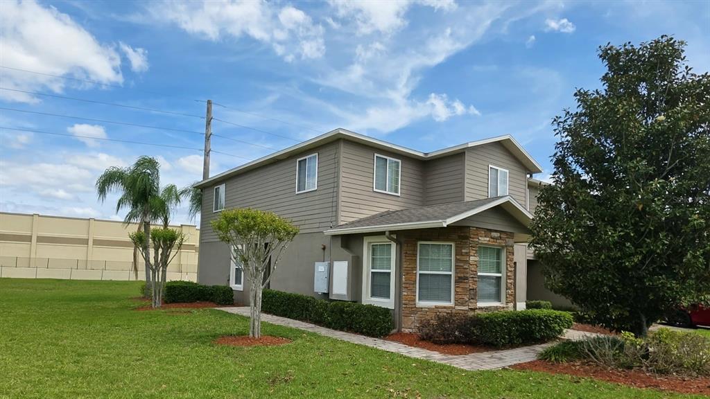 A two-story house with tan siding, stone accents, and a paved walkway on a lawn — 1861 CHATHAM PLACE DRIVE, ORLANDO, FL