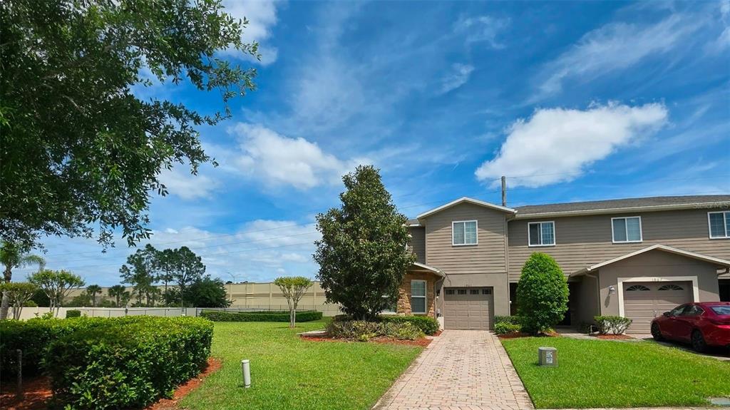 A two-story townhouse with a paved driveway, a small front lawn, and a red car — 1861 CHATHAM PLACE DRIVE, ORLANDO, FL
