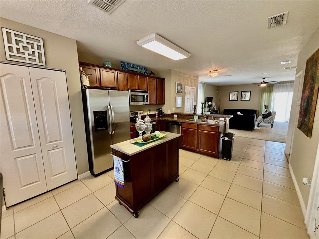 A kitchen with dark wood cabinets, stainless steel appliances, and a mobile island — 1861 CHATHAM PLACE DRIVE, ORLANDO, FL