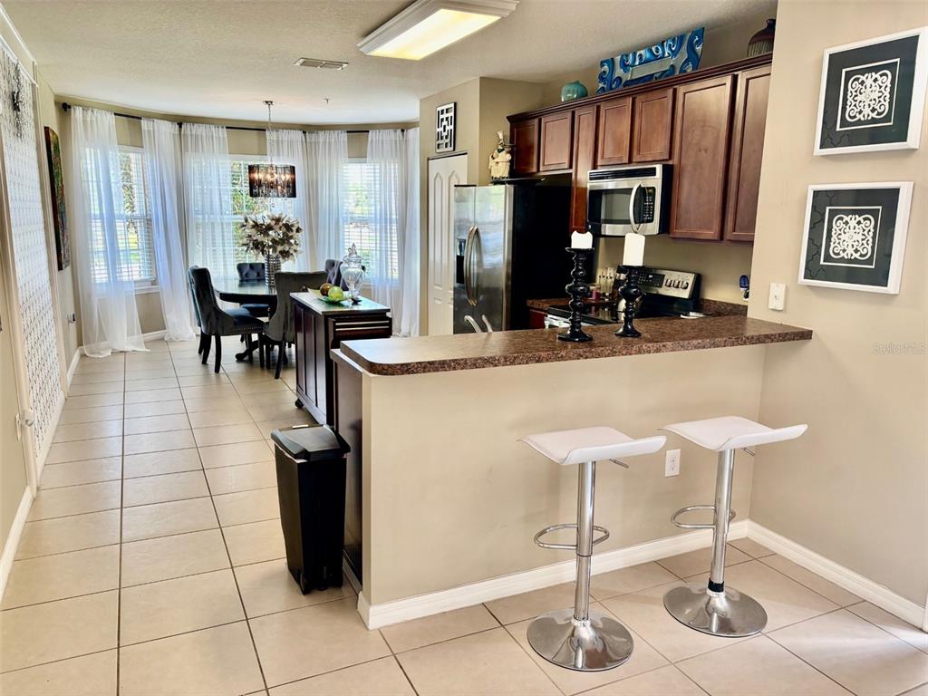 A kitchen with dark wood cabinets and a breakfast bar overlooks a dining area — 1861 CHATHAM PLACE DRIVE, ORLANDO, FL