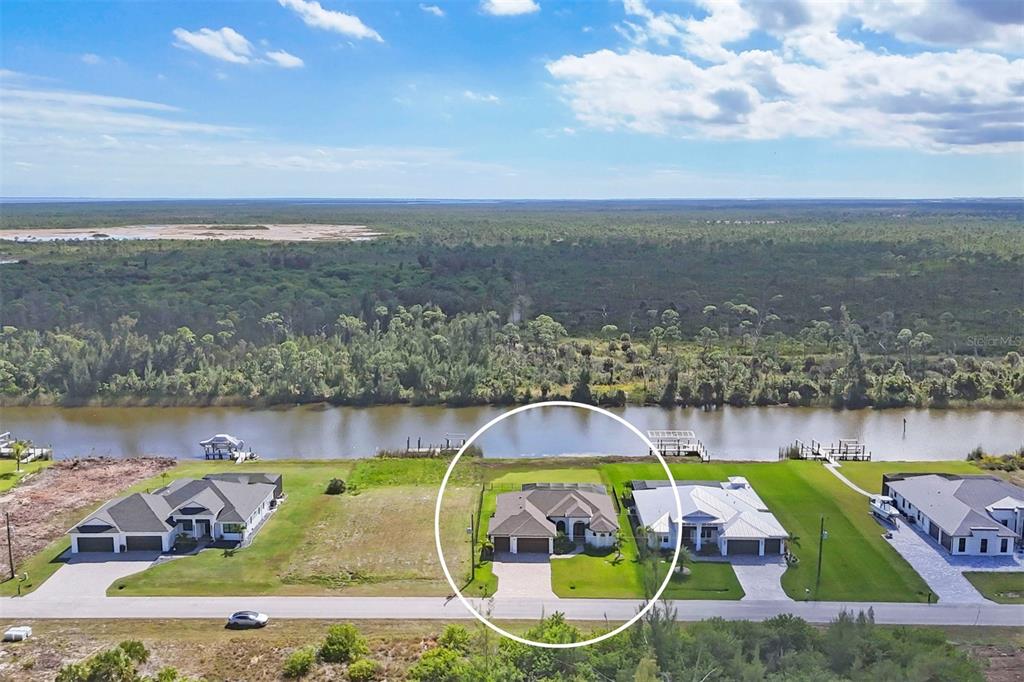 An aerial view shows a house with a pool cage situated along a waterfront canal — 16660 LIGGETT CIRCLE, PORT CHARLOTTE, FL