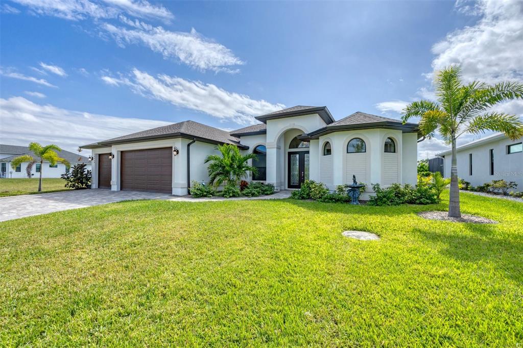 A single-story house with a brown garage, arched windows, and a palm tree in front — 16660 LIGGETT CIRCLE, PORT CHARLOTTE, FL