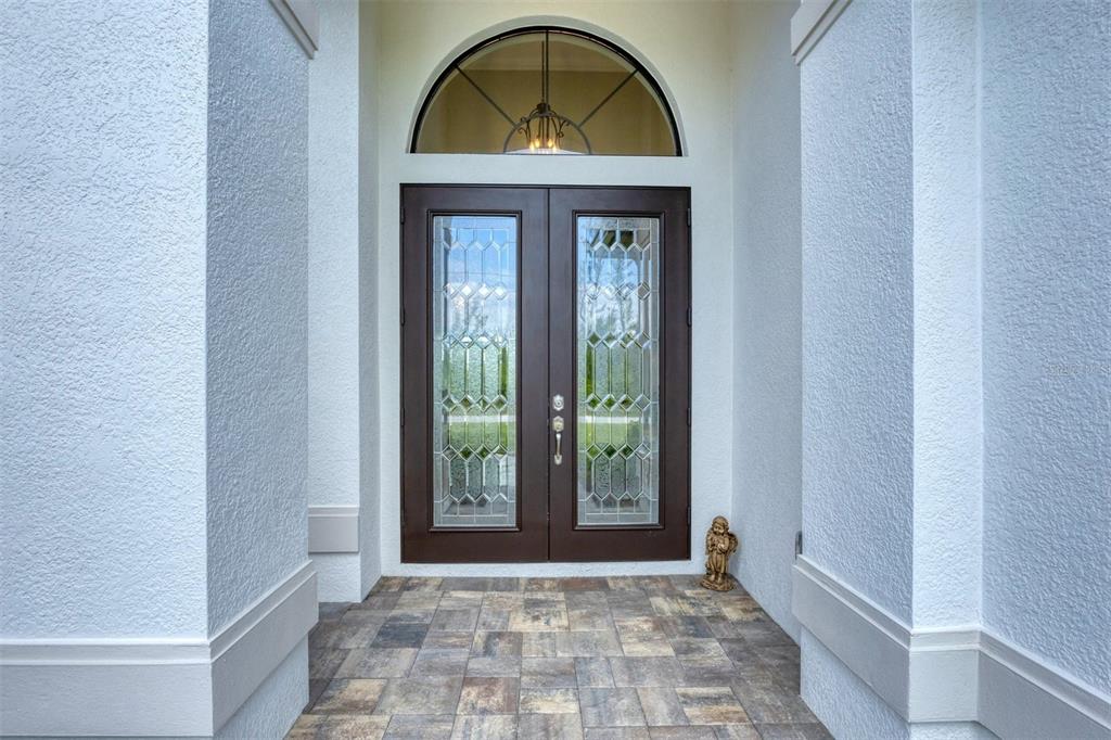A front entryway features double doors with glass inserts beneath an arched transom window — 16660 LIGGETT CIRCLE, PORT CHARLOTTE, FL