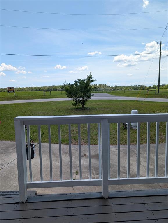 A view of a grassy yard and a small tree from a wooden porch — 7083 SE 166TH AVENUE, OCKLAWAHA, FL