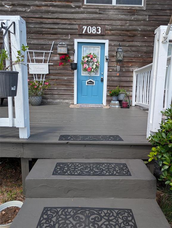 A wooden deck with gray steps leads to a blue front door on a house — 7083 SE 166TH AVENUE, OCKLAWAHA, FL