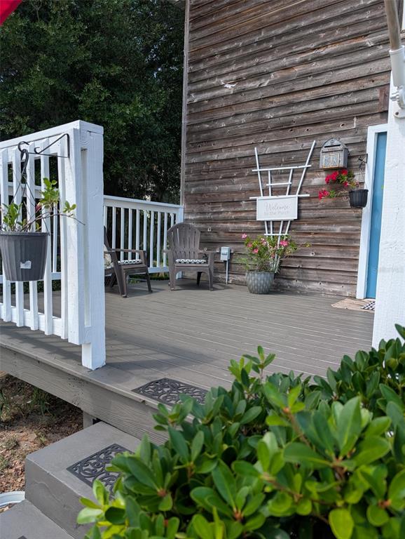 A wooden deck features two chairs, a white trellis, and potted plants against a house — 7083 SE 166TH AVENUE, OCKLAWAHA, FL