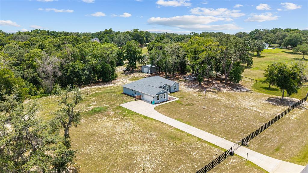 An aerial view shows a single-story house with a concrete driveway and a fenced yard — 10254 SE 118TH LANE, BELLEVIEW, FL