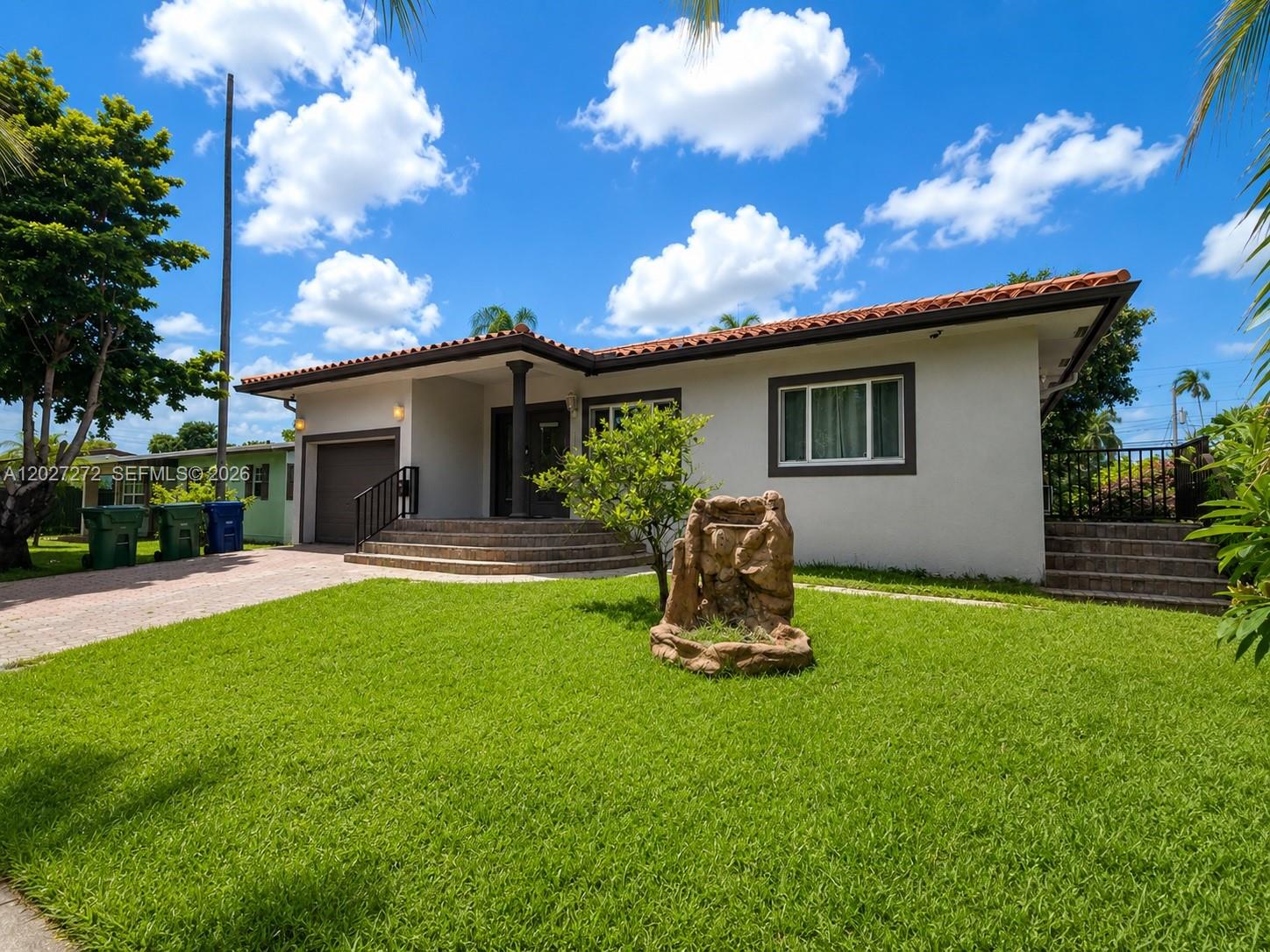 A single-story house with a tiled roof, a front lawn, and a decorative stone fountain — 1101 NE 2nd St, Hallandale Beach FL 33009, HALLANDALE BEACH, FL