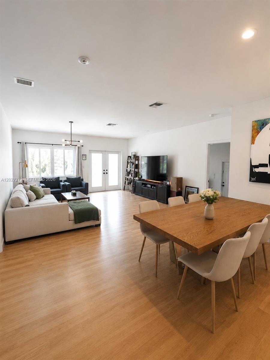 An open-concept living and dining area features light wood flooring, white walls, and modern furniture — 1101 NE 2nd St, Hallandale Beach FL 33009, HALLANDALE BEACH, FL