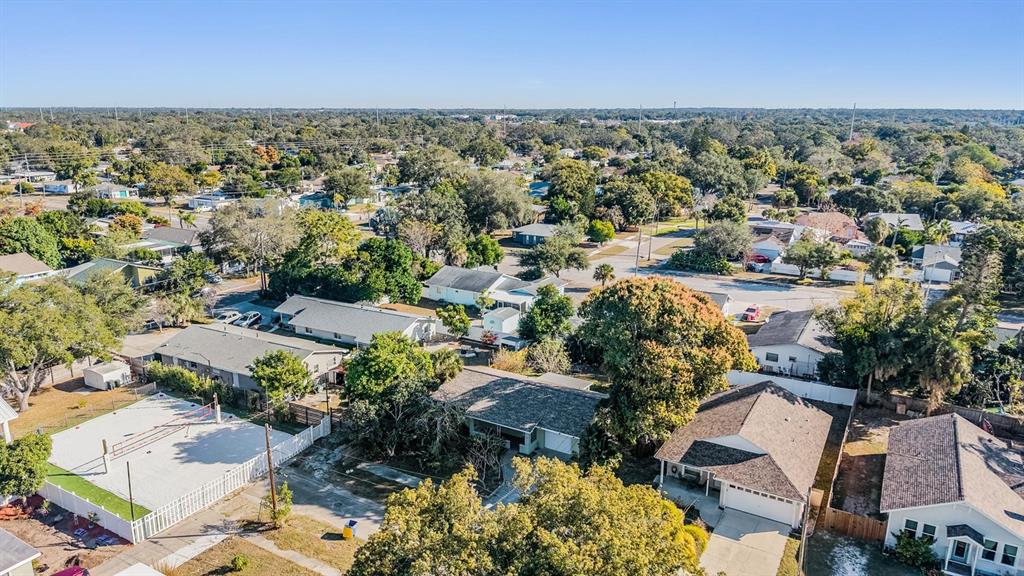 An aerial view shows a residential neighborhood with houses, trees, and a sand volleyball court — 2025 PLAZA DOLORES, CLEARWATER, FL
