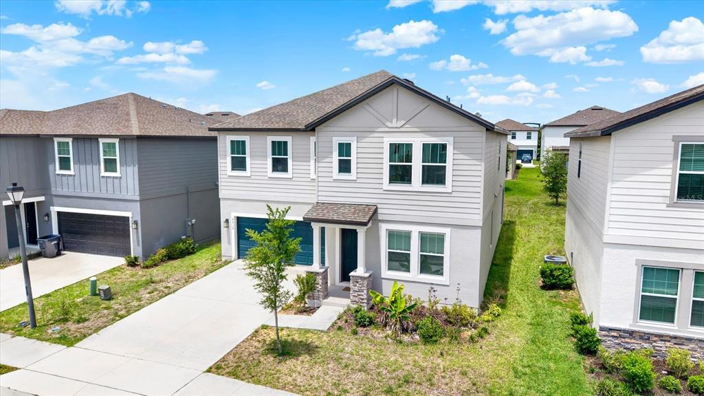 A two-story suburban house with light gray siding, a shingled roof, and a concrete driveway — 2310 LANCASHIRE STREET, DAVENPORT, FL