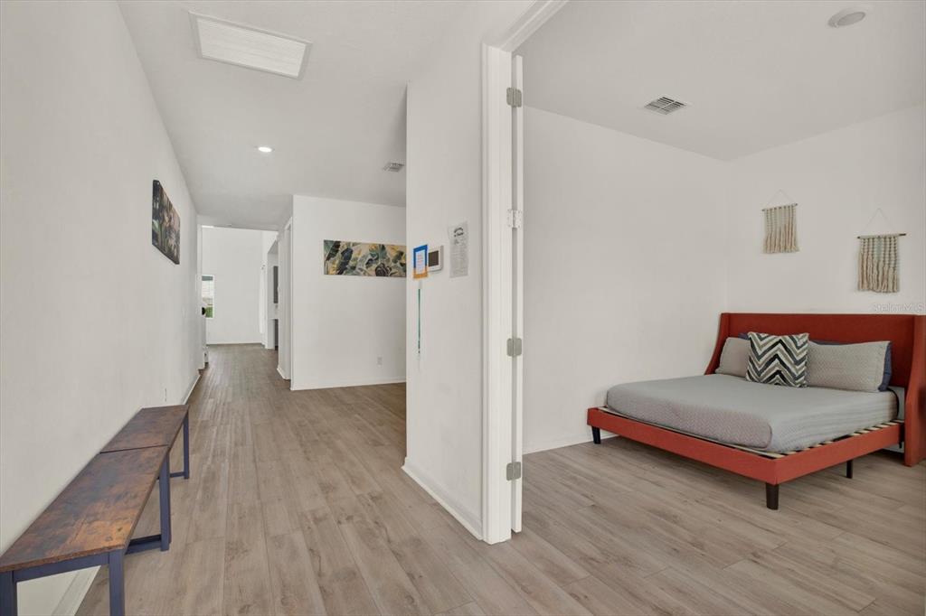 A bedroom with a red bed frame opens into a hallway with wood-look flooring — 2310 LANCASHIRE STREET, DAVENPORT, FL