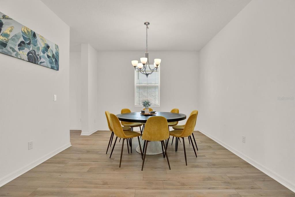 A dining room features a round table with yellow chairs under a modern chandelier — 2310 LANCASHIRE STREET, DAVENPORT, FL
