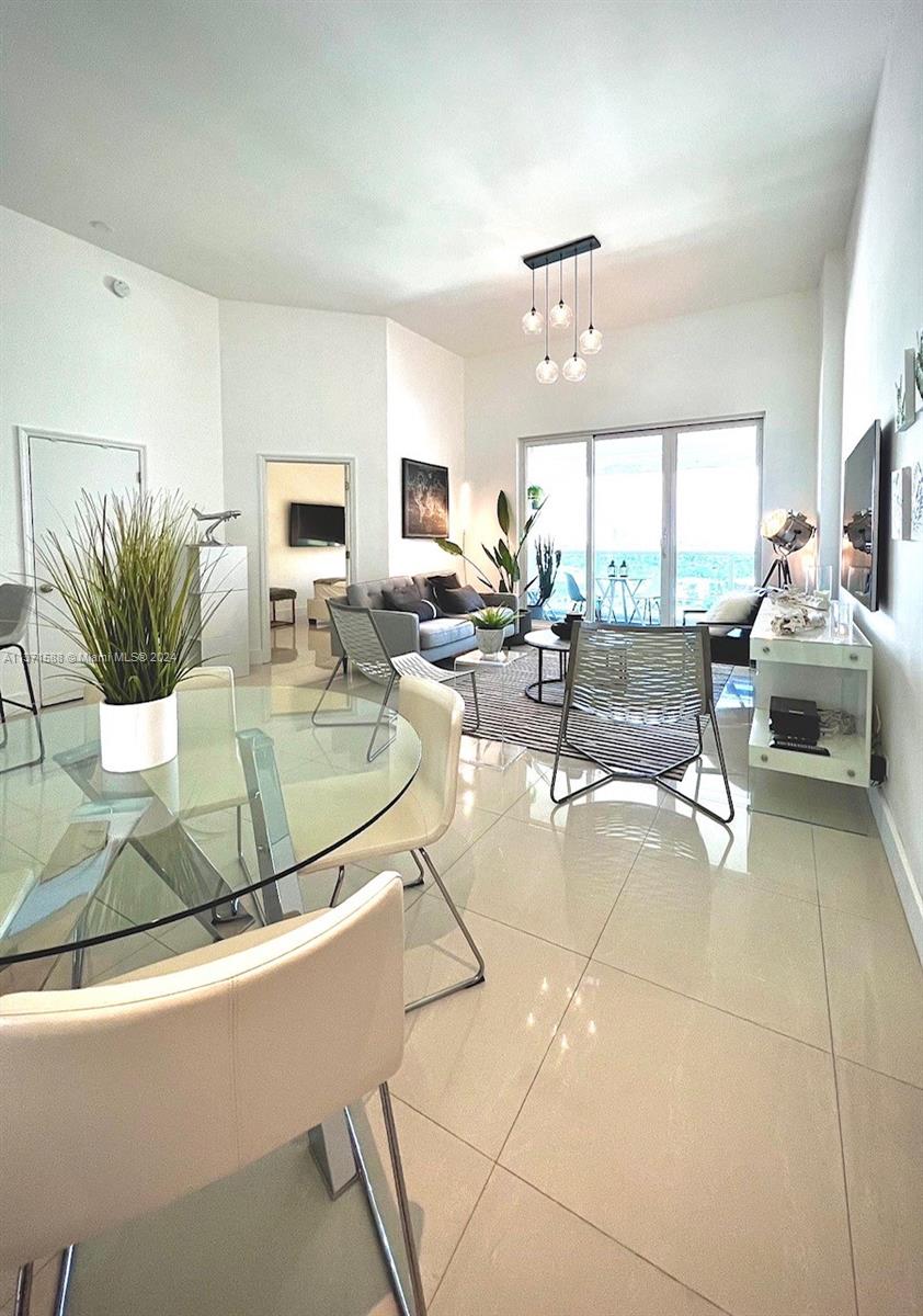 A bright living and dining area features tile floors, a glass table, and balcony access — 2301 Collins Ave # 1626, Miami Beach FL 33139, MIAMI BEACH, FL