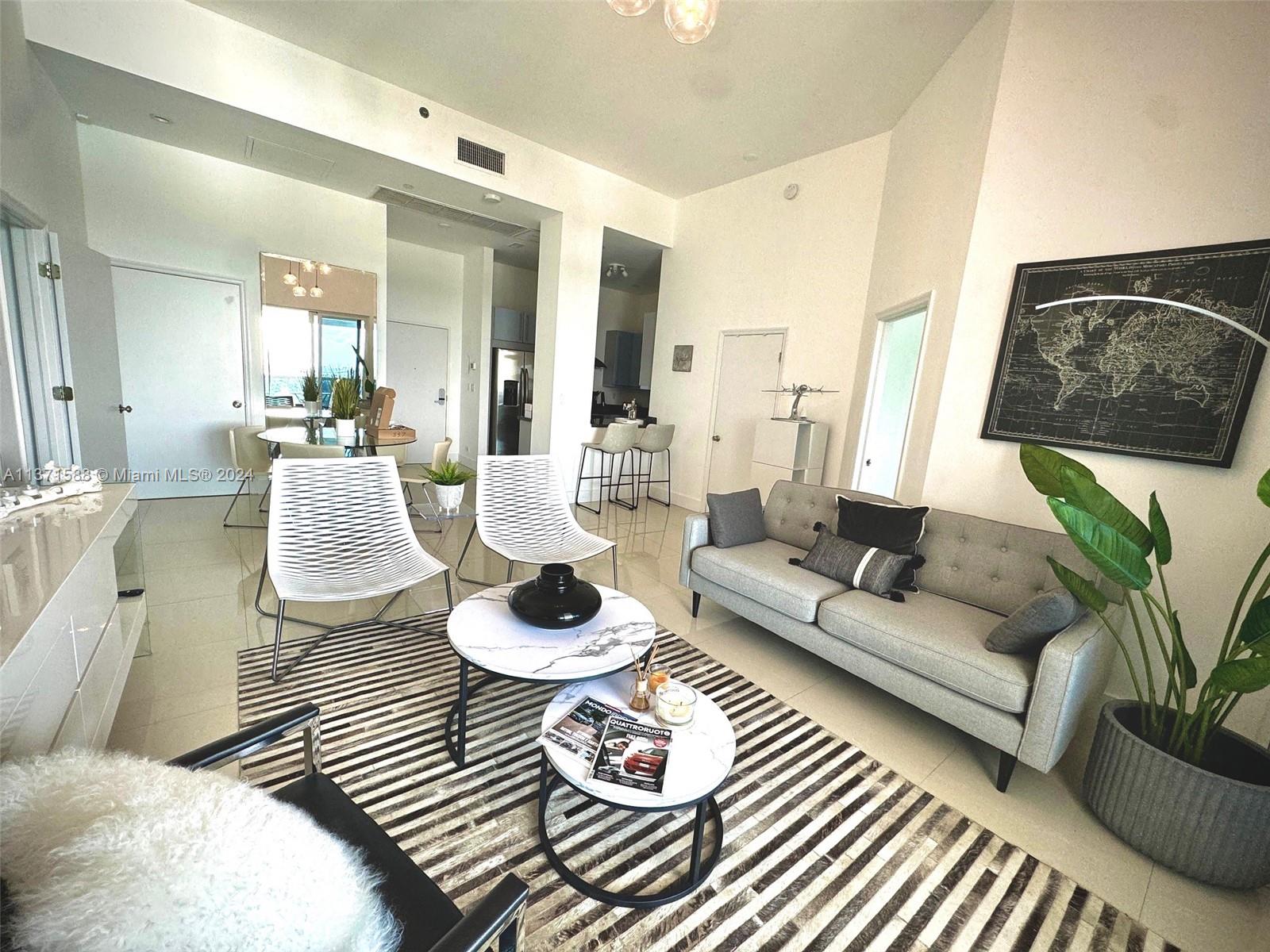 A modern living room features a grey sofa, two white chairs, and a striped rug — 2301 Collins Ave # 1626, Miami Beach FL 33139, MIAMI BEACH, FL