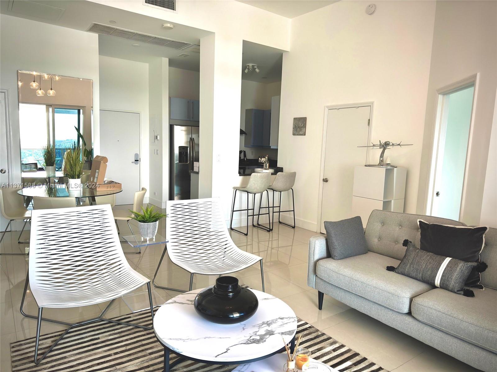 A modern living room features a grey sofa, two white chairs, and a marble coffee table — 2301 Collins Ave # 1626, Miami Beach FL 33139, MIAMI BEACH, FL