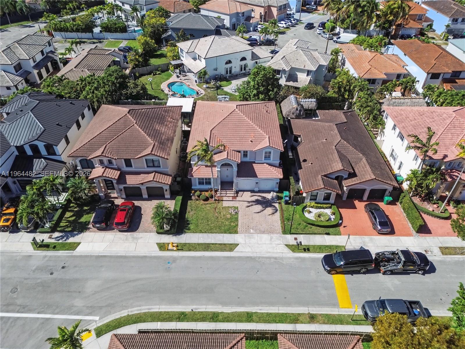 An aerial view shows three suburban houses with tiled roofs and driveways along a street — 9260 SW 153rd Psge, Miami FL 33196, MIAMI, FL