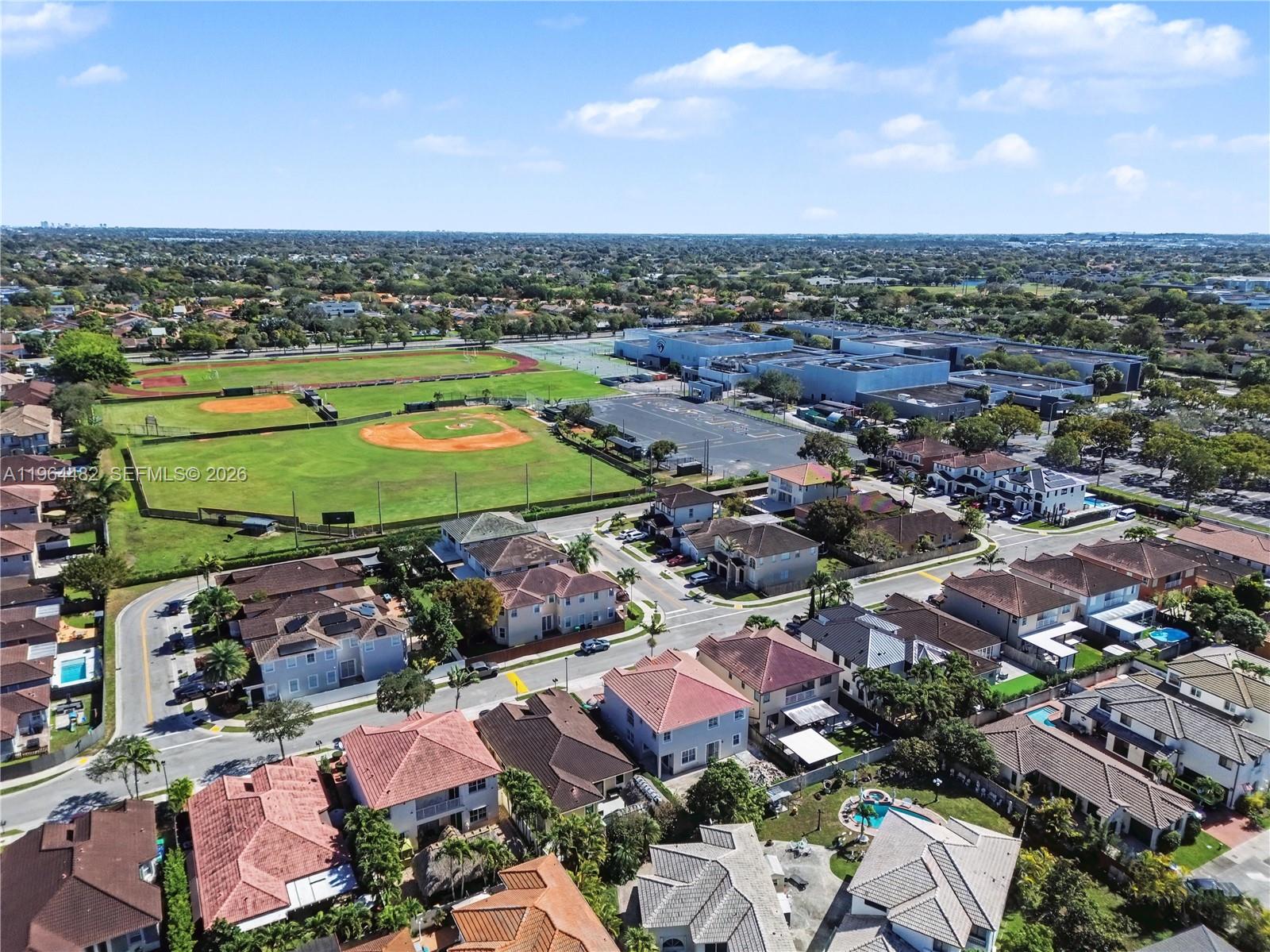 An aerial view shows a residential neighborhood adjacent to a large school sports complex — 9260 SW 153rd Psge, Miami FL 33196, MIAMI, FL