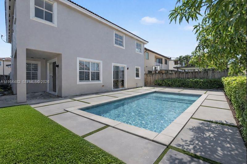 A two-story house exterior features a rectangular swimming pool surrounded by concrete pavers and grass — 9260 SW 153rd Psge, Miami FL 33196, MIAMI, FL