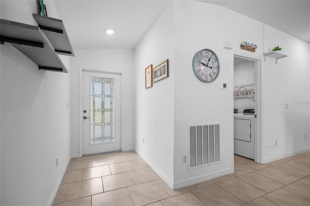 An entryway features tile flooring, a glass-paneled front door, and a doorway leading to laundry — 137 HERCULES DRIVE, ROTONDA WEST, FL