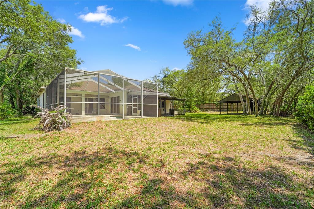 A backyard view of a house with a screened-in pool enclosure and a detached shed — 9183 NIGHTINGALE ROAD, WEEKI WACHEE, FL