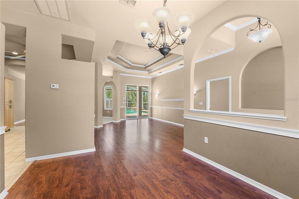 A dining area with wood floors, a chandelier, and an arched opening to another room — 9183 NIGHTINGALE ROAD, WEEKI WACHEE, FL