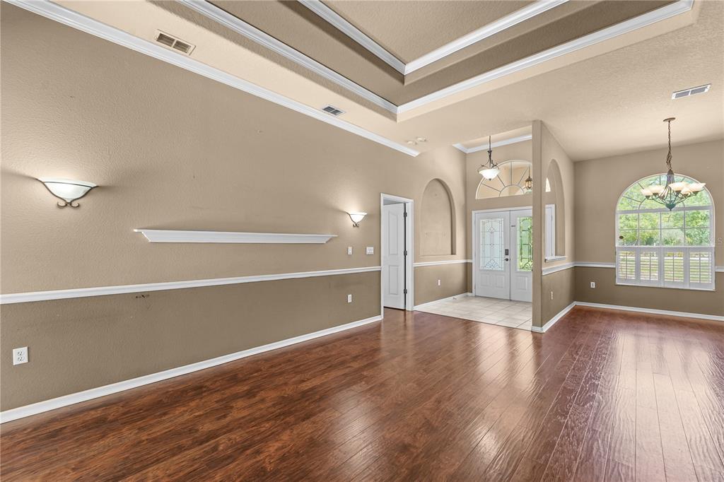A living room with wood floors, a tray ceiling, and a view of the entryway — 9183 NIGHTINGALE ROAD, WEEKI WACHEE, FL