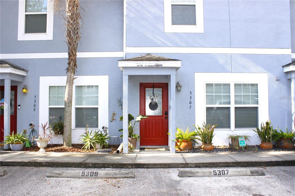 The exterior of a blue two-story townhouse features a red front door and potted plants — 5307 TERRAZA COURT, TEMPLE TERRACE, FL