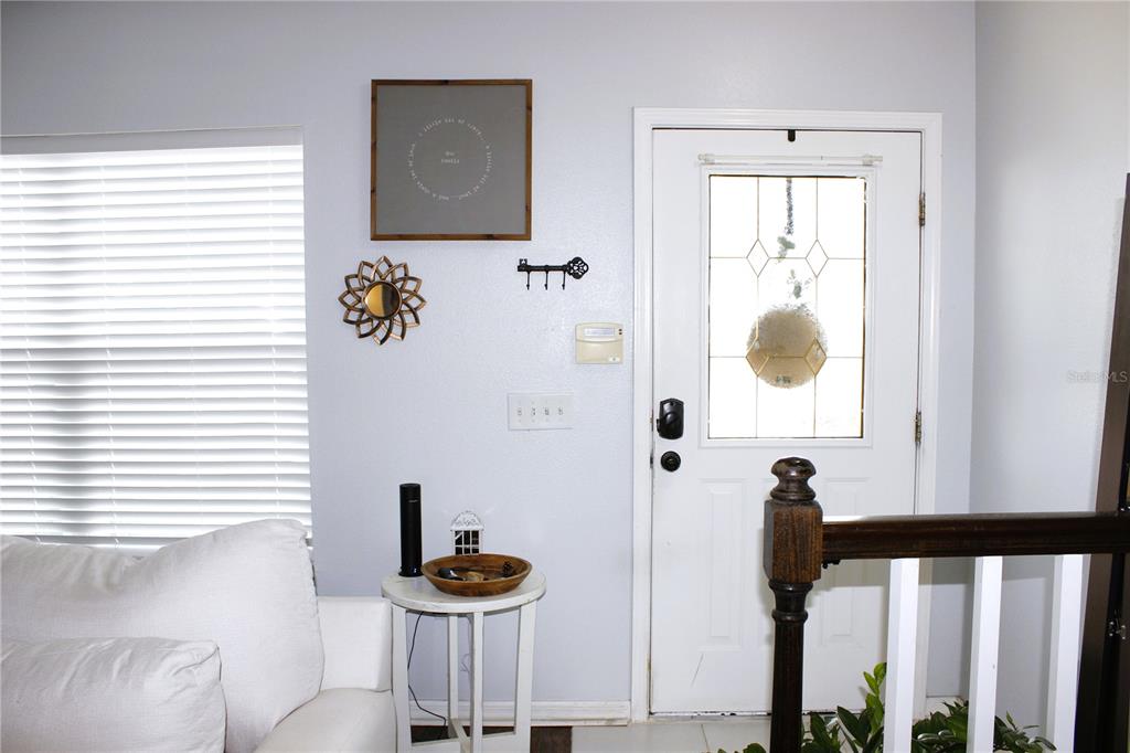 A living room entryway features a white door, a side table, and wall decor — 5307 TERRAZA COURT, TEMPLE TERRACE, FL