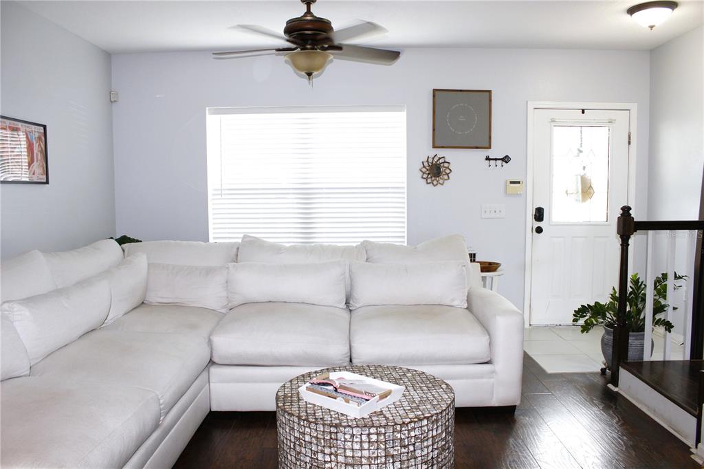 A living room features a white sectional sofa, a round textured coffee table, and hardwood flooring — 5307 TERRAZA COURT, TEMPLE TERRACE, FL
