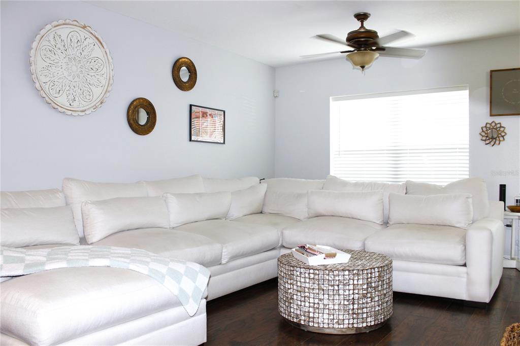 A living room features a large white sectional sofa, a round textured coffee table, and decor — 5307 TERRAZA COURT, TEMPLE TERRACE, FL