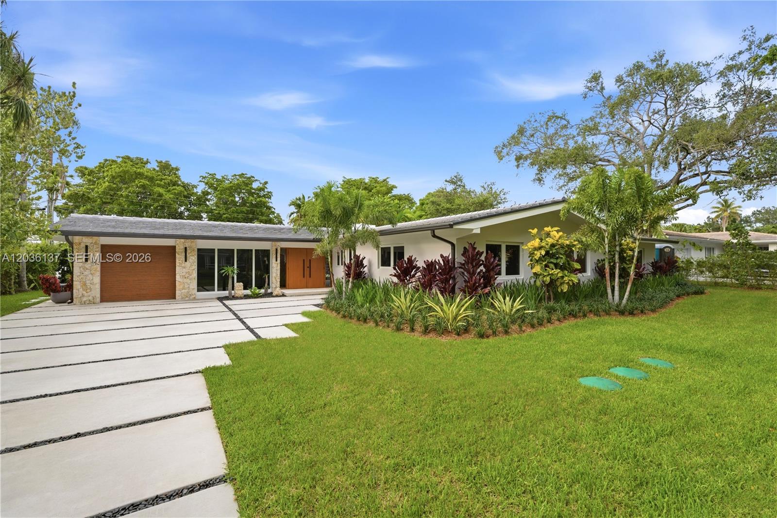 A single-story house features a concrete driveway, stone accents, and a landscaped front yard — 1451 Urbino Ave, Coral Gables FL 33146, CORAL GABLES, FL
