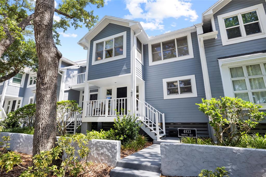A blue two-story townhouse exterior features a white porch, stairs, and a parking sign — 4833 W FLAMINGO RD, TAMPA, FL