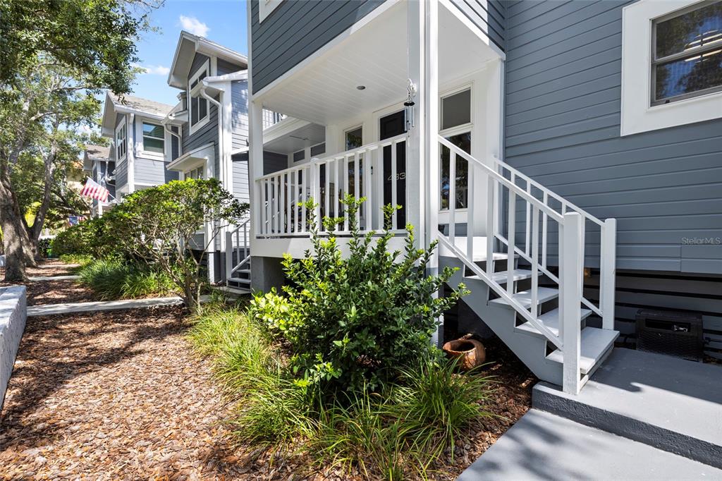A gray house features a white front porch, stairs, and a landscaped yard — 4833 W FLAMINGO RD, TAMPA, FL