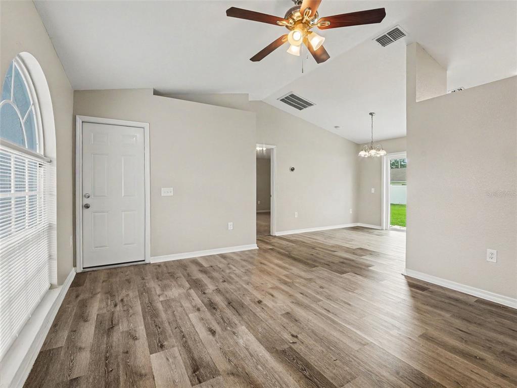An interior view of a living room with wood-look flooring, a ceiling fan, and vaulted ceilings — 645 LINNET COURT, POINCIANA, FL