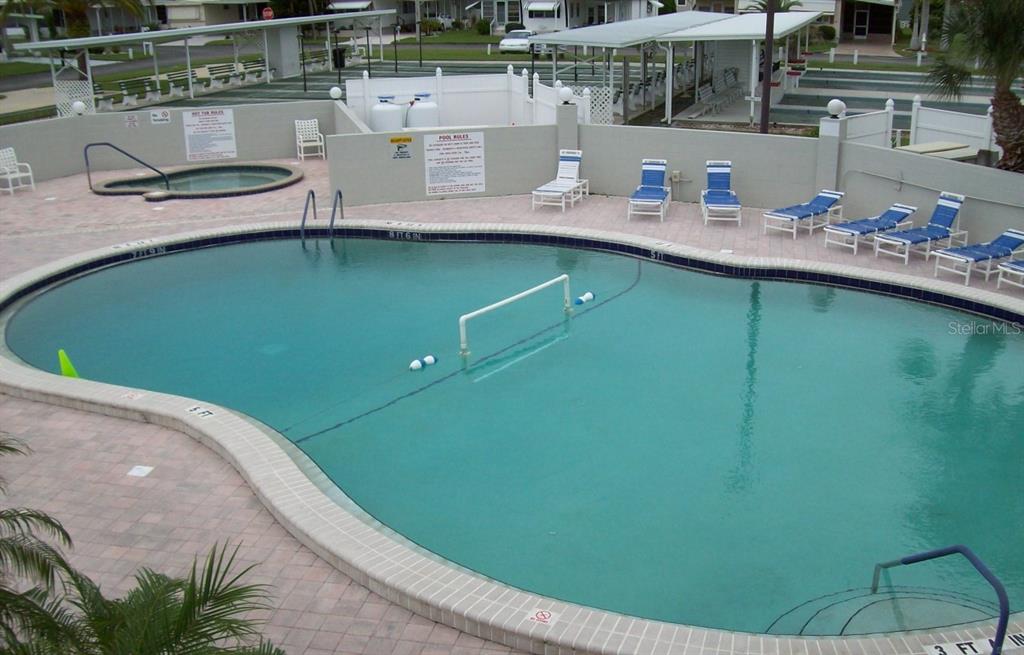 An outdoor swimming pool with a volleyball net, lounge chairs, and a small hot tub — 217 WOLVERINE AVENUE, NORTH PORT, FL