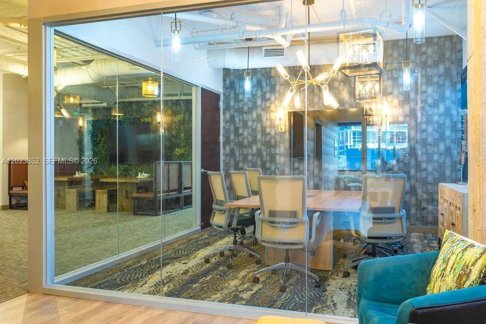 A glass-walled conference room features a wooden table, office chairs, and a modern chandelier — 515 N Flagler Dr, West Palm Beach FL 33401, WEST PALM BEACH, FL