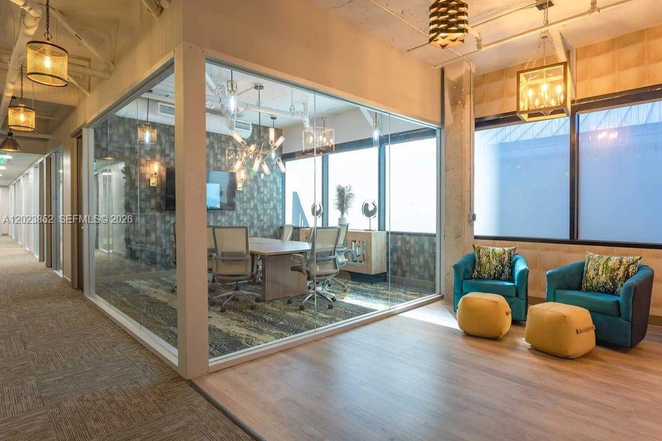 A glass-walled conference room sits beside a lounge area with two armchairs and ottomans — 515 N Flagler Dr, West Palm Beach FL 33401, WEST PALM BEACH, FL