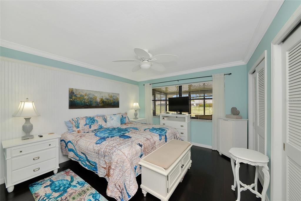 A bedroom features a bed with a sea turtle quilt, white furniture, and light blue walls — 6220 29TH AVENUE W UNIT 6220, BRADENTON, FL
