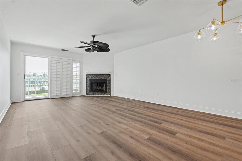 A living room features wood-look flooring, a corner fireplace, a ceiling fan, and sliding doors — 269 MADEIRA CIRCLE, ST PETERSBURG, FL