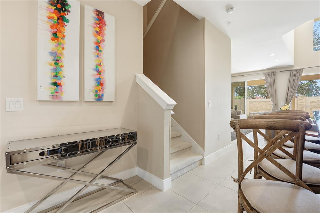 A foyer features a metallic console table, two abstract paintings, and stairs leading to a landing — 3113 BRASILIA AVENUE, KISSIMMEE, FL