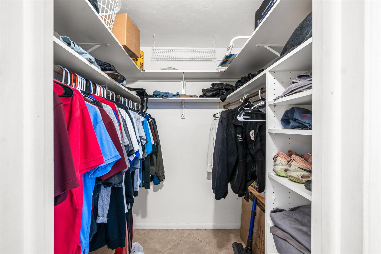 A walk-in closet features white shelving, hanging clothes, and a tiled floor — 750 SE 6th Avenue # 125, Deerfield Beach FL 33441, DEERFIELD BEACH, FL