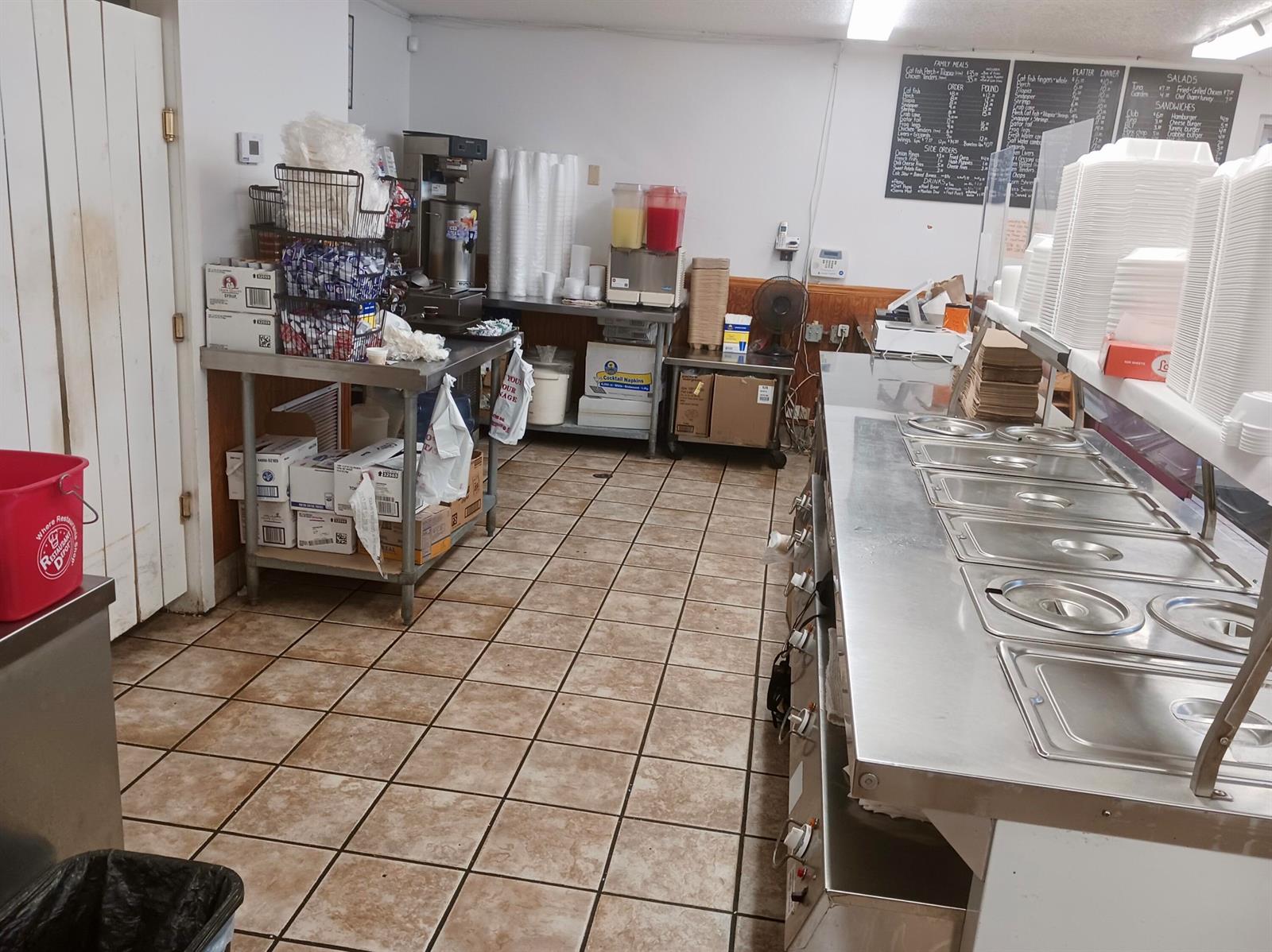 A commercial kitchen features stainless steel prep tables, tiled flooring, and a menu board — 149 S Lake Avenue, Pahokee FL 33476, PAHOKEE, FL