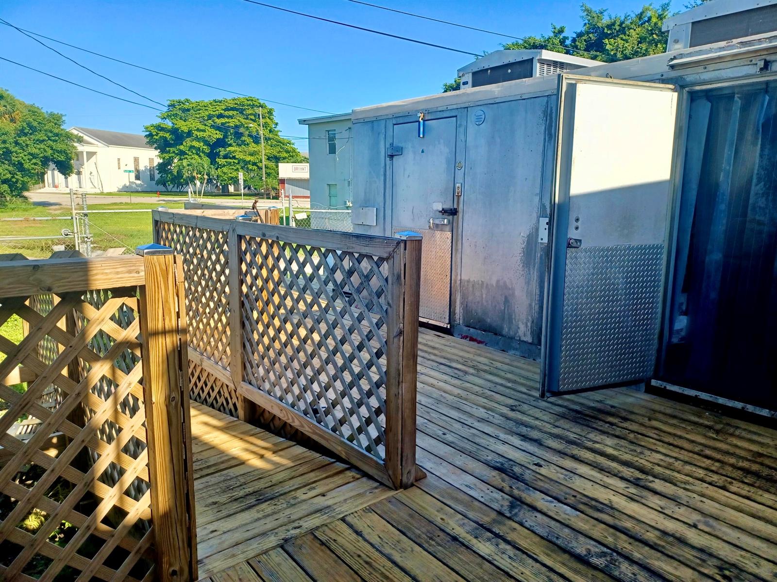A wooden deck features a lattice railing and a large metal walk-in cooler unit — 149 S Lake Avenue, Pahokee FL 33476, PAHOKEE, FL