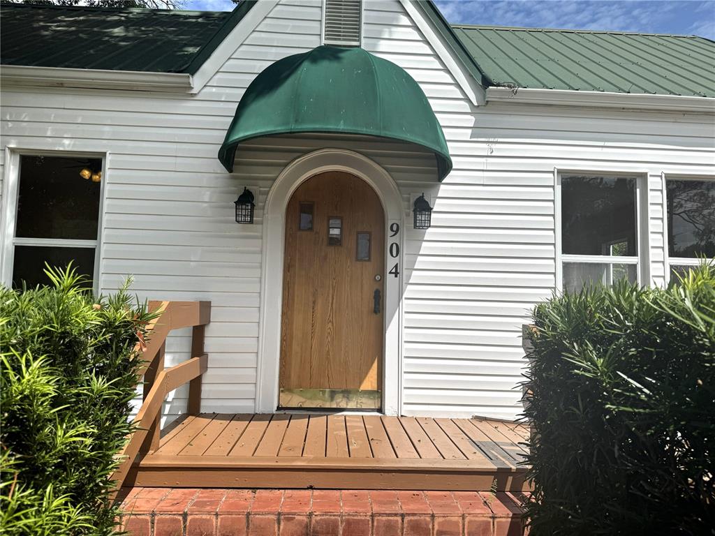 The exterior of a house features white siding, a green awning, and a wooden door — 904 E MOODY BOULEVARD, BUNNELL, FL
