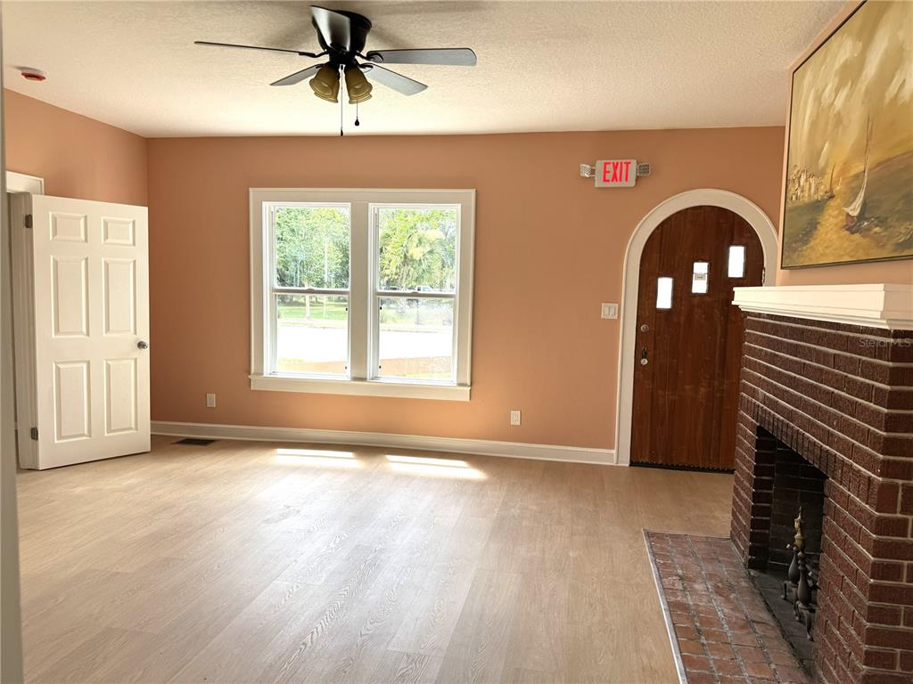 A living room features light wood flooring, a brick fireplace, and an arched wooden front door — 904 E MOODY BOULEVARD, BUNNELL, FL