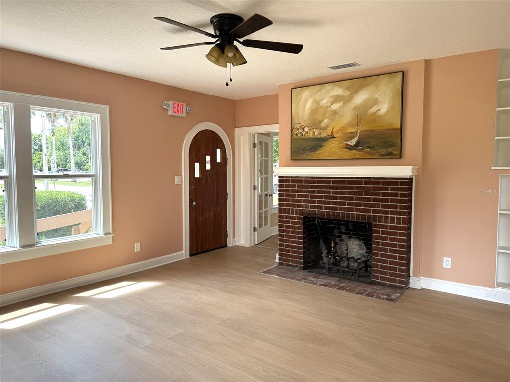 A living room features light wood flooring, peach walls, a brick fireplace, and an arched door — 904 E MOODY BOULEVARD, BUNNELL, FL