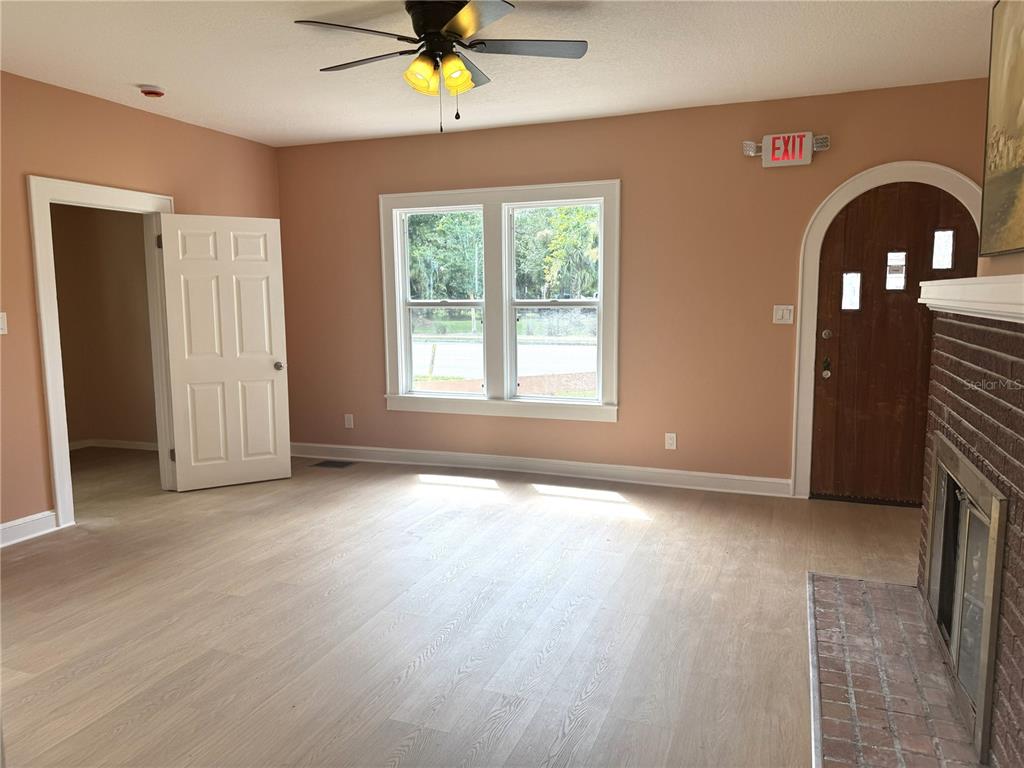 A living room features light wood flooring, peach walls, a ceiling fan, and a fireplace — 904 E MOODY BOULEVARD, BUNNELL, FL