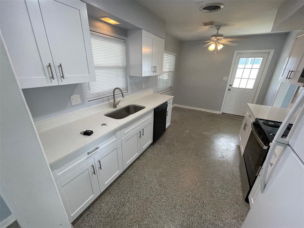 A kitchen features white cabinets, light countertops, a stainless steel sink, and speckled flooring — 520 SENECA TRAIL, MAITLAND, FL